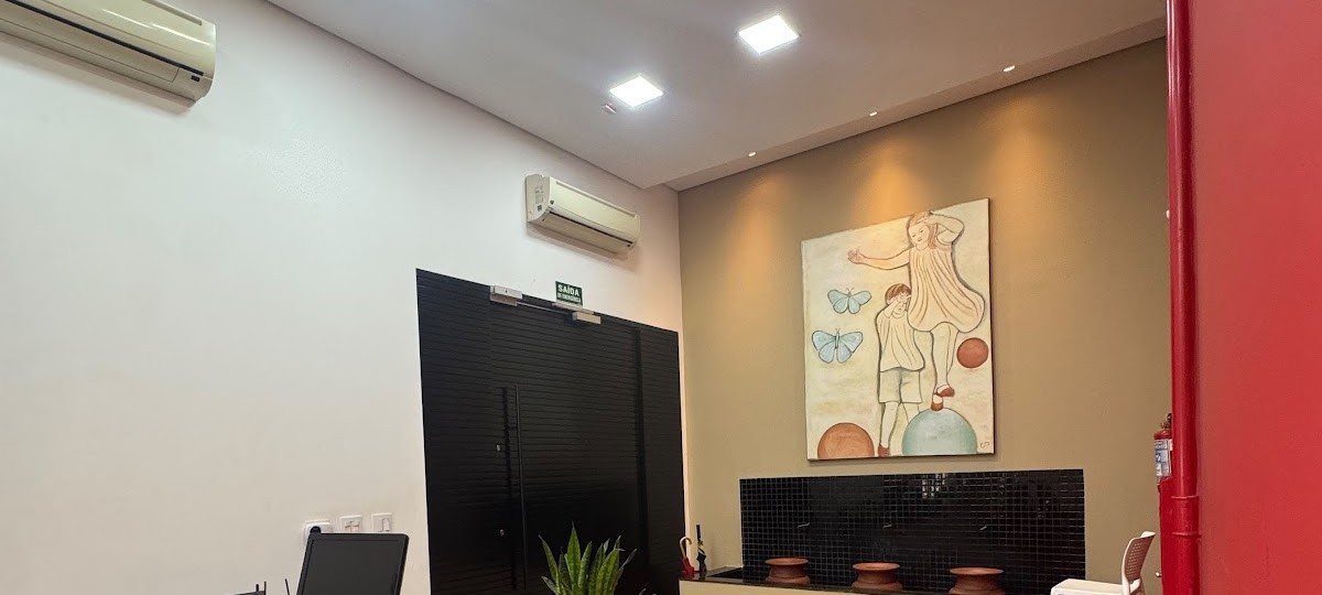 A sala de atendimento: parede terra com um quadro de traço art-nouveau, portas pretas e vasos de cerâmica